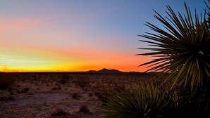 A desert landscape at sunset with sparse vegetation and distant mountains. - Unique off Grid Desert Retreat, California, USA (Hesperia)