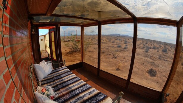 A room with a bed, a view of a desert landscape, and a large window. - Unique off Grid Desert Retreat, California, USA (Hesperia)