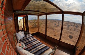 Une chambre avec un lit, une vue sur un paysage désertique et une grande fenêtre.