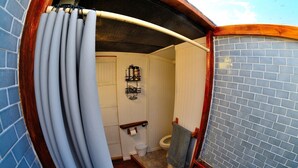 A bathroom with a blue-tiled wall, a wooden door, a white toilet, and a towel hanging on the wall. - Unique off Grid Desert Retreat, California, USA (Hesperia)