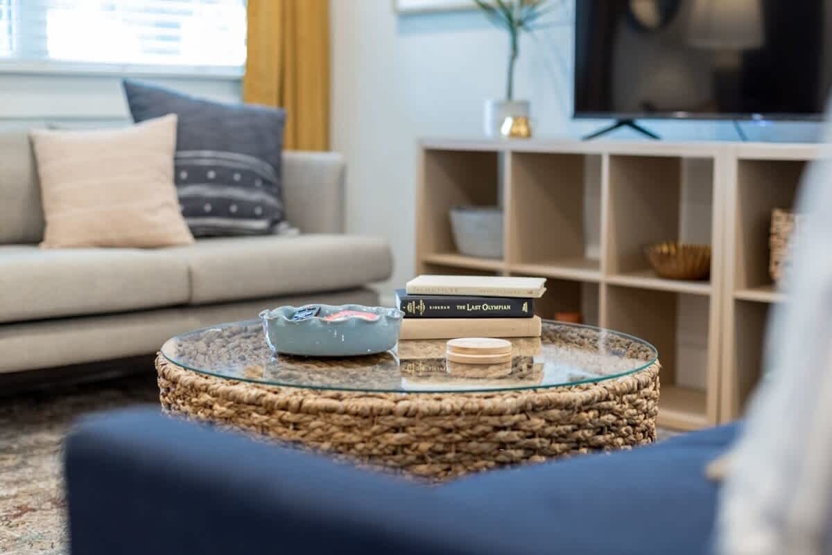A living room with a round glass coffee table, a sofa, a bookshelf, and a television.
