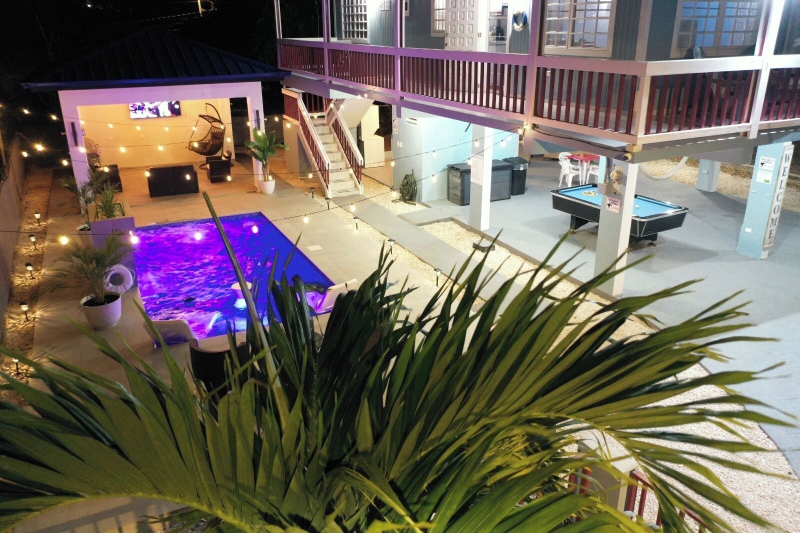 A two-story building with a pool, outdoor seating, and a staircase.