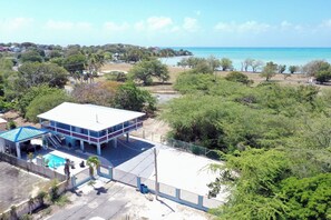 Un edificio con piscina, rodeado de árboles y vistas al océano.