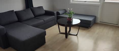 A modern living room with a sectional sofa, a round coffee table, and a potted plant.