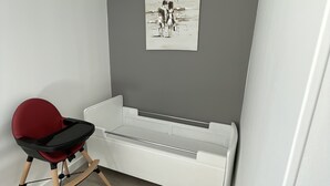 Ein kleines Zimmer mit einem weißen Stauraum, einem roten Sessel und einem Schwarz-Weiß-Kunstwerk an der Wand.