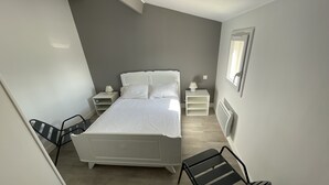 Ein Schlafzimmer mit einem Bett, zwei Nachttischen, einem Sessel und einer Heizung.