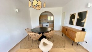 A dining area with a round table, wicker chairs, and a modern light fixture. - Serenity & design T3, 2 terraces seaview 600m beach (Praia da Luz)