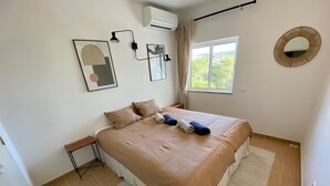 A bedroom with a bed, a window, a wall-mounted air conditioner, and a mirror. - Serenity & design T3, 2 terraces seaview 600m beach (Praia da Luz)
