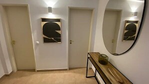 A hallway with two doors, a bench with a glass container, and a large mirror on the wall. - Serenity & design T3, 2 terraces seaview 600m beach (Praia da Luz)