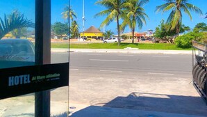 A hotel with a clear view of the street, palm trees, and a yellow building in the background. - POUSADA MORADAS (Aracaju)