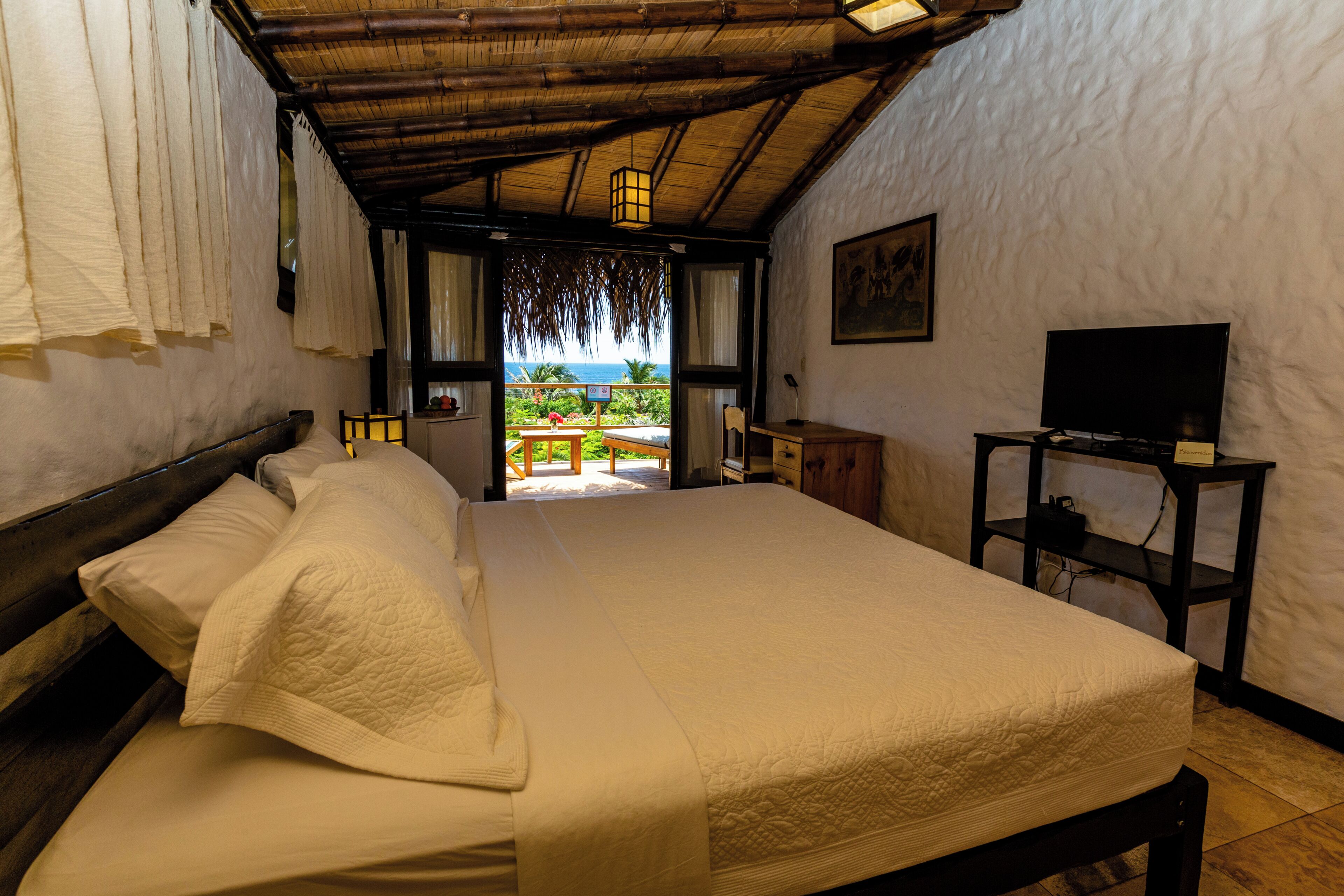 Una habitación con cama, televisión y vista al océano.