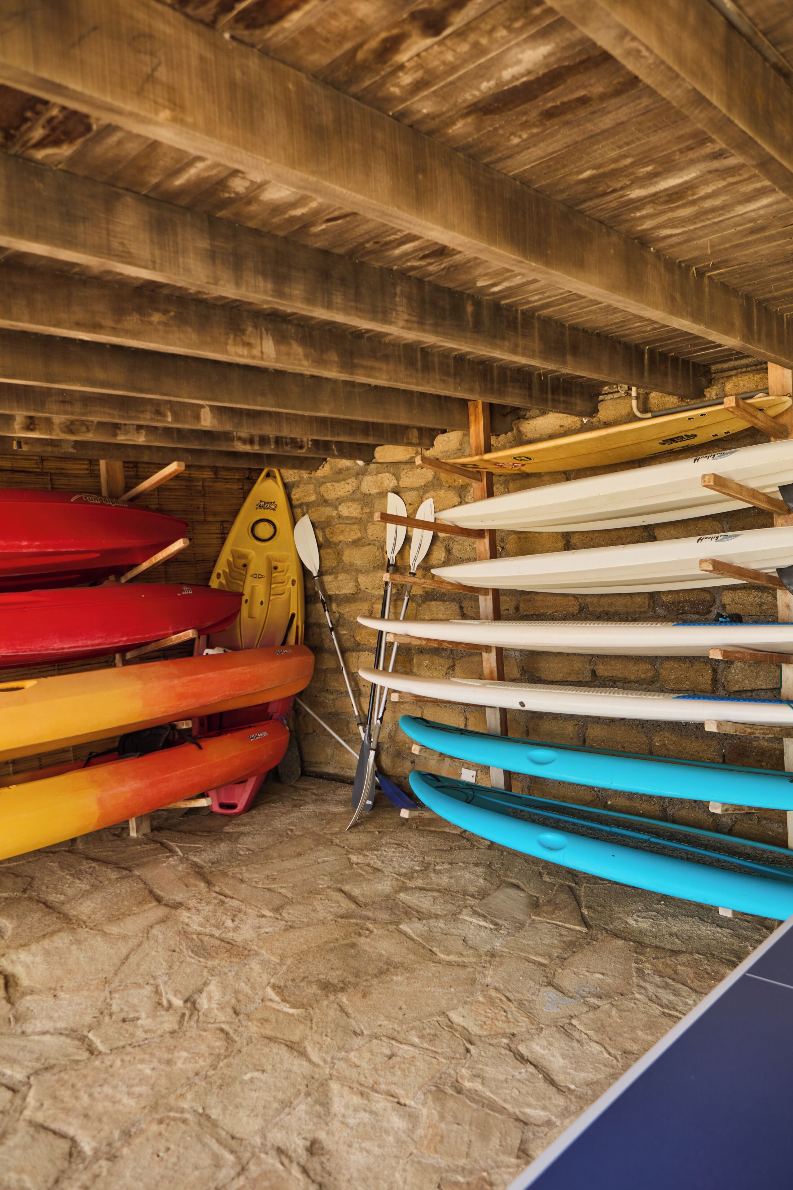 Un espace de rangement contenant différents kayaks et pagaies.