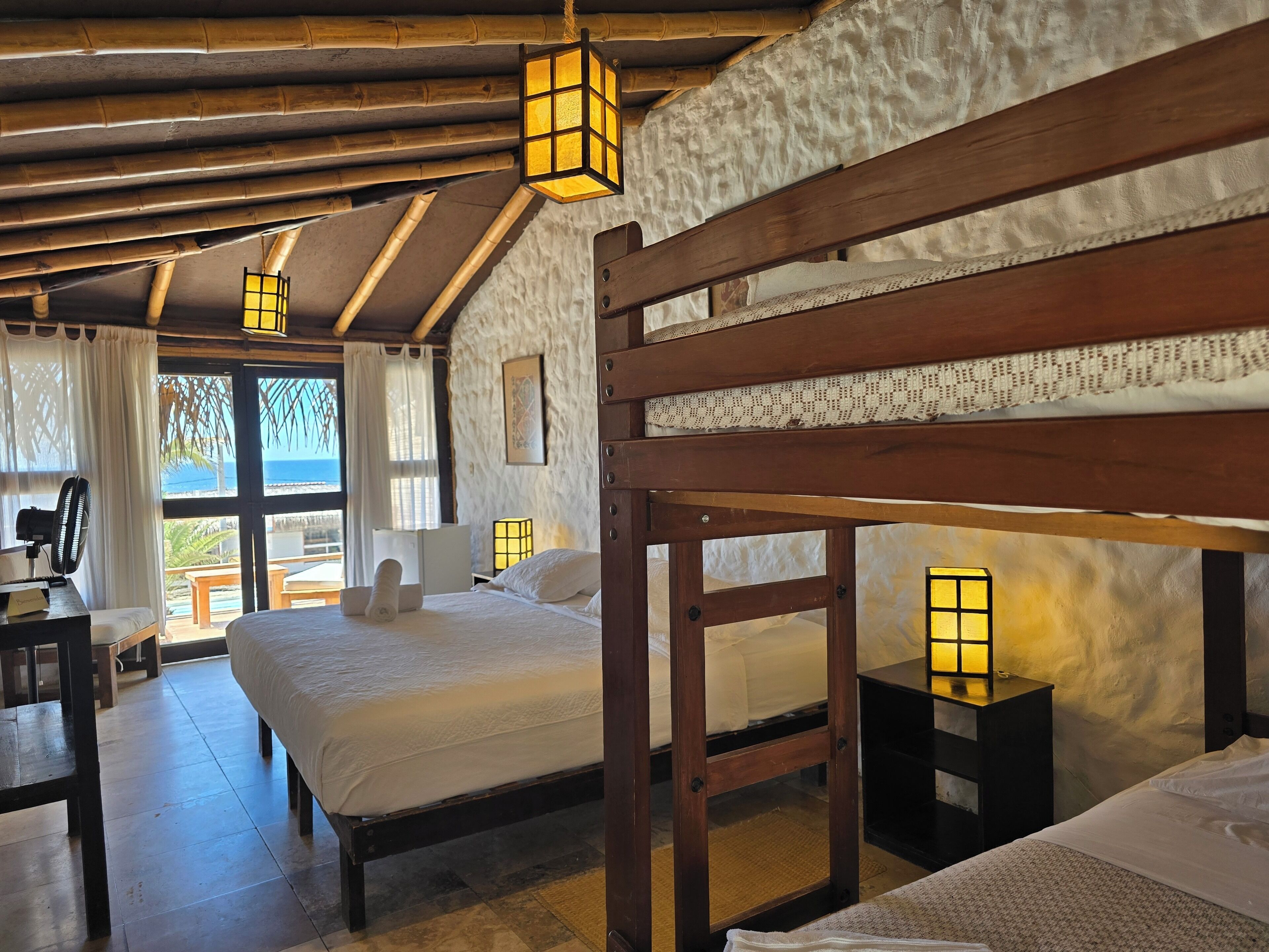 Una habitación rústica con cama, mesitas de noche y vista al mar.