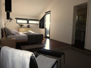 A bedroom with a bed, bedside table, lamp, and a view of the bathroom.