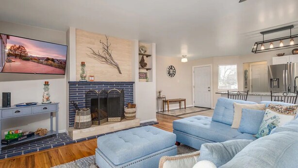 A modern living room with a fireplace, blue sofas, a flat-screen TV, and a kitchen in the background. - Orange Door (Sparks)