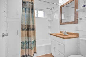 A bathroom with a shower, a sink with a mirror, and a toilet. - Lakefront 3-bedroom cottage with private dock & amazing sunset view (Arkdale)