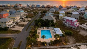 A coastal residential area with houses, a swimming pool, and a sunset view.