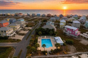 A coastal residential area with houses, a swimming pool, and a sunset view.