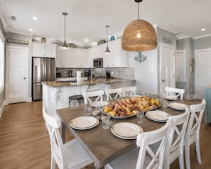 A modern kitchen with white cabinets, stainless steel appliances, and a dining area with a wooden table set for six.