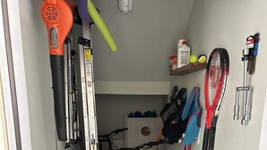 A narrow garage with bicycles, a lawnmower, and a sign for a bike rental service.