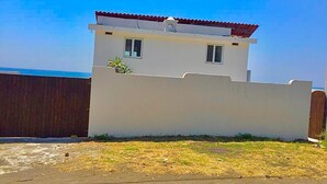 Un edificio blanco con techo rojo y una cerca de madera al frente.
