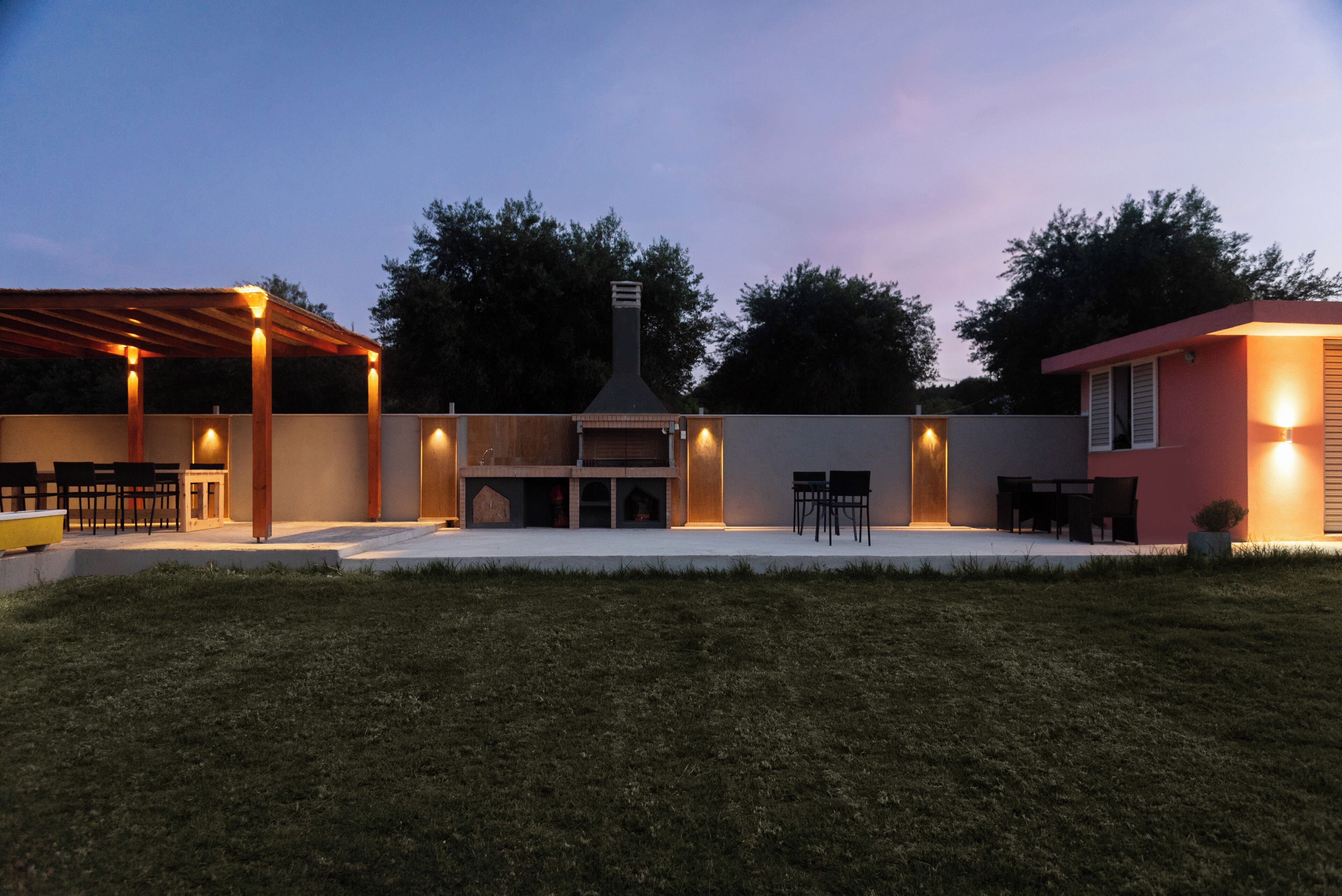 A backyard with a barbecue area, outdoor seating, and a covered patio.