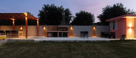 A backyard with a barbecue area, outdoor seating, and a covered patio.
