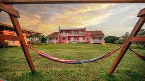 Una casa grande con un balcón, una hamaca y un patio cubierto de césped.