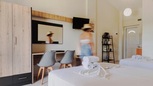 Una habitación de hotel con cama, escritorio, dos sillas, televisor y armario.