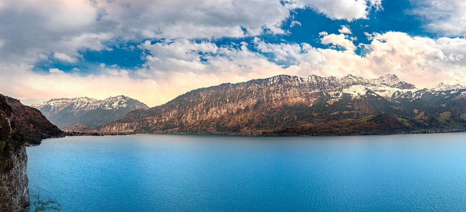 Un lago de montaña con aguas cristalinas azules y picos nevados al fondo.
