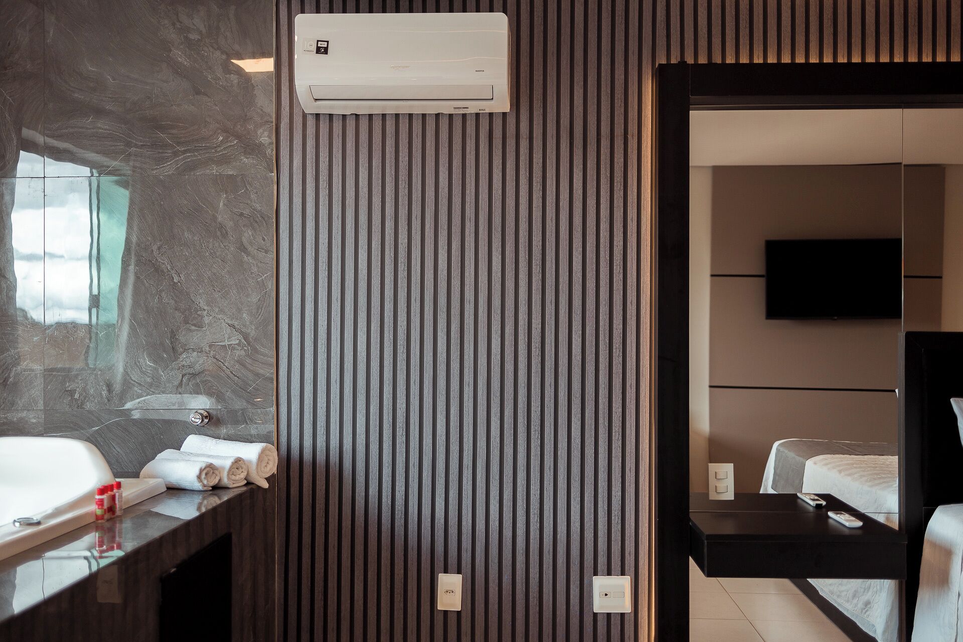 Un baño moderno con pared de mármol, lavamanos empotrado y un perchero.