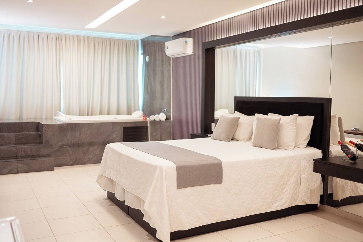 A modern bedroom with a large bed, a built-in desk, and a large mirror.