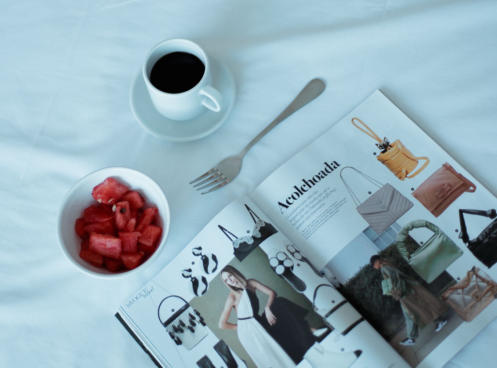 Una revista sobre una mesa con un tazón de sandía y una taza de café.