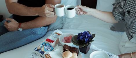 Una bandeja de desayuno con pasteles, un pastel y un ramo de flores sobre una cama.