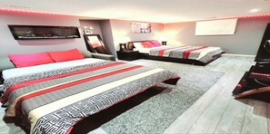 Hotelkamer met twee bedden, elk voorzien van beddengoed met een patroon, een flatscreen televisie aan de muur, een bureau met stoel, en een groot raam.
