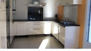 A modern kitchen with white cabinets, a black countertop, and a stainless steel range hood.