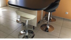 A kitchen area with a black countertop, a white sink, and two bar stools.