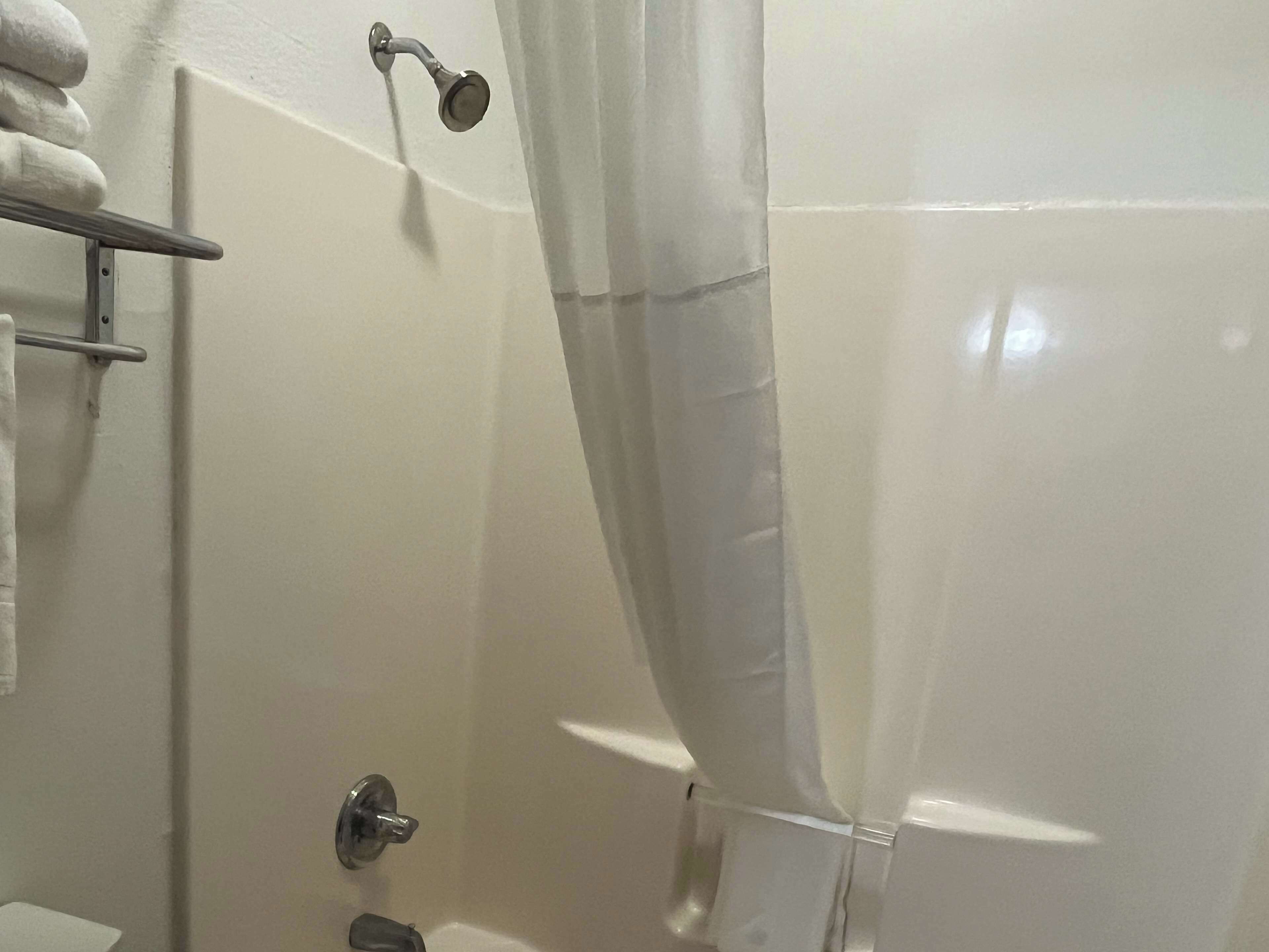 A bathroom with a shower curtain, a towel rack, and a toilet.