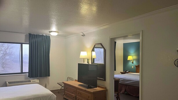 A hotel room with two beds, a desk with a TV, a dresser, and a window with curtains. - Motel 6 Portland, IN (Portland)