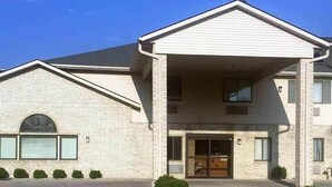A two-story building with a brick facade, a covered entrance, and a clear sky. - Motel 6 Portland, IN (Portland)