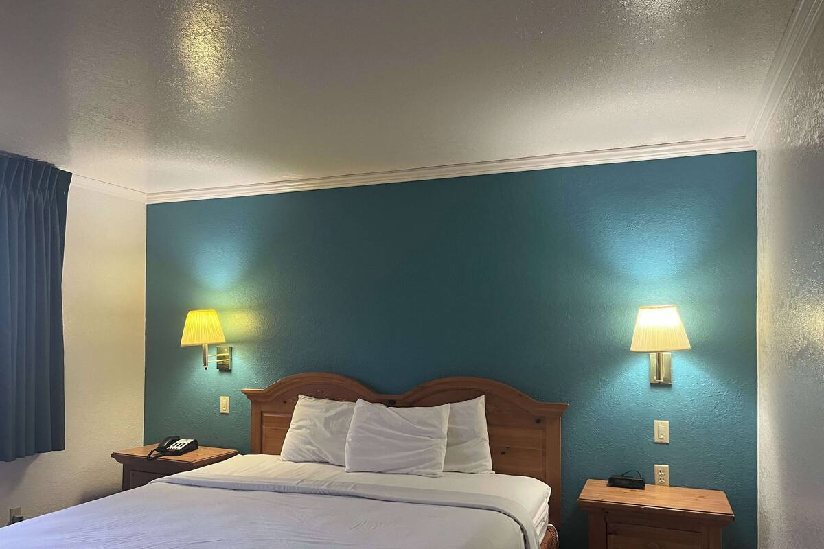 A hotel room with a bed, two bedside tables, a lamp on each table, and a telephone on one table.