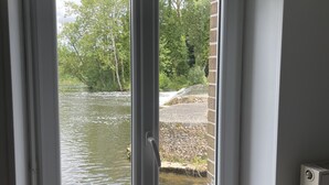 Une pièce avec vue sur une rivière, accessible par une porte-fenêtre coulissante.