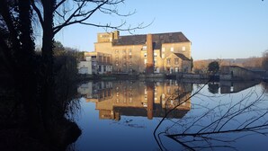 Un bâtiment historique doté de nombreuses fenêtres, dont le reflet se mire dans l’eau.