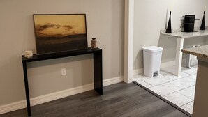 Een kamer met een donkerhouten console tafel waarop een lijstwerk met een schilderij, een klein decoratief potje en een witte kaars staan.