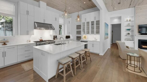 A modern kitchen with white cabinetry, a large island, and wooden flooring. - 92 East Water Street | 4 Bedroom with Pool & Hot Tub! (Inlet Beach)