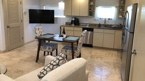 Una cocina compacta con comedor, un televisor de pantalla plana y un refrigerador.