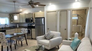 Una sala moderna con una mesa de centro de vidrio, un sofá y un comedor con sillas estampadas.