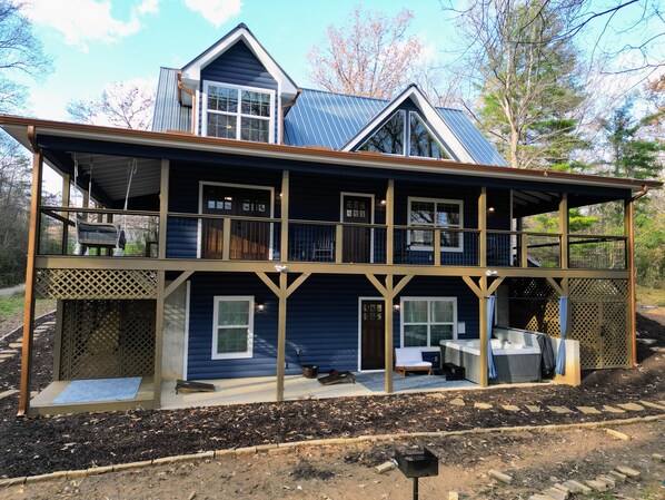 A two-story house with a balcony, a porch, and a covered outdoor seating area.