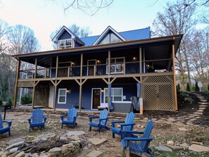 A two-story building with a balcony, outdoor seating area with chairs, and a stone pathway.