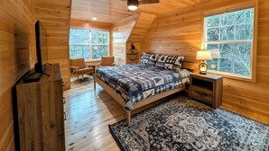 Une chambre confortable avec un lit, un bureau et une chaise, des murs en bois et de grandes fenêtres.
